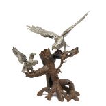 Two Japanese silver coloured metal falcons on a tree