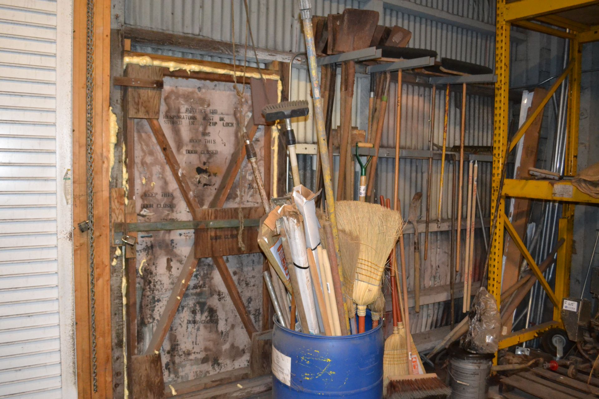 roll of reinforced plastic, roll of paper, asst. brooms and shovels along wall