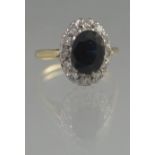 OVAL SAPPHIRE AND DIAMOND CLUSTER RING. The oval sapphire an estimated 6 x 8mm.