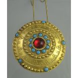 UNMARKED YELLOW METAL CIRCULAR MEDALLION PENDANT decorated with applied gold beading and paste red