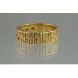 AN 18CT GOLD BARK EFFECT WEDDING RING BY ALAN MARTIN GARD. Width 5mm. Ring Size L. Weight 5.8g. (B.