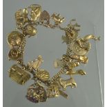 9CT GOLD CHARM BRACELET with heart shaped padlock clasp and thirty one charms. Weight 60.9g aprpox.