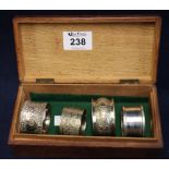 Single silver engine turned napkin ring and three white metal napkin rings in oak box. (B.P.