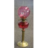 Early 20th Century brass double burner oil lamp with red glass reservoir and brass pedestal base,