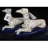 Pair of Staffordshire style recumbent stylised dalmations on a blue oval base. (2) (B.P. 24% incl.