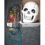 Modern skull telephone with light up red eyes, together with another clear plastic telephone.