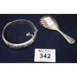 Silver plated shell shaped caddy spoon and an engraved silver hinged bangle. 1.6 troy ozs approx.