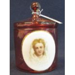 Cranberry glass, straight sided jar and cover with applied painted porcelain portrait panel. (B.P.