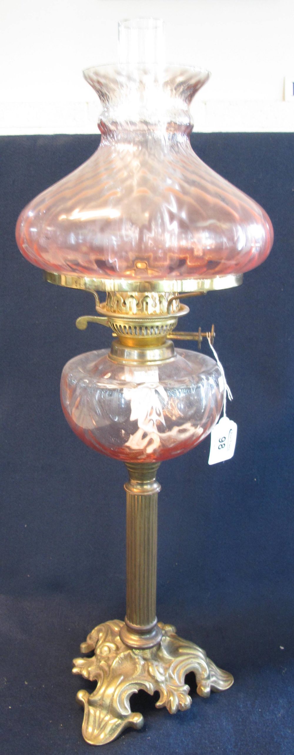 Brass double burner oil lamp with glass reservoir and brass pedestal base with a coloured glass