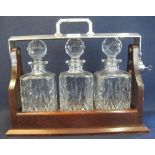Modern mahogany three bottle tantalus with plated mounts and three square section spirit decanters