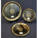 Set of three graduated Japanned Tole ware metal circular trays, over gilded with central initials.