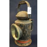 Japanned metal cylindrical shaped railway hand lantern with interchangeable lenses and two handles.