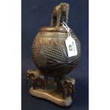 Asian coconut shell vase and cover with three elephant shaped supports on a triform base,