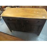 Elm Ercol sideboard having two drawers and two blind panelled fielded cupboards standing on stile