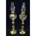 Pair of small single burner brass oil lamps with glass reserviors and brass bases, clear chimneys.