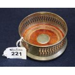 Small pierced silver bottle coaster with wooden base geometric decoration.