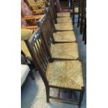 Set of six oak Arts and Crafts slat backed kitchen chairs on rush seats,