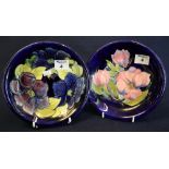 Two Moorcroft art pottery dishes with tube lined floral decoration on dark blue ground,