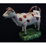 Swansea pottery cow creamer with splashed decoration on a naturalistic oval shaped base.