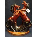Glazed pottery study of two rearing/fighting horses on wooden base, unmarked. (B.P. 24% incl.