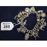 A silver charm bracelet with various silver charms including; a coracle, spinning wheel etc. (B.P.