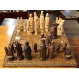 Heavily carved chess set on wooden base with foliate decoration,