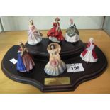 A set of six miniature Royal Doulton figurines on a Royal Doulton stepped mahogany finish wooden