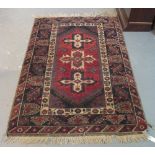 Middle Eastern red ground rug with geometric decoration and cruciform panels to the red field. (B.