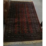 Middle Eastern design rug on a red ground with repeating gul and geometric foliate decoration. (B.P.
