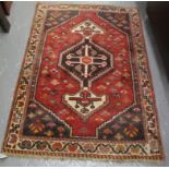 Small Middle Eastern design carpet on a red ground with geometric and foliate banding. (B.P.