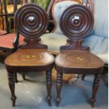 Pair of Victorian mahogany hall chairs with circular raised backs on a moulded seat standing on