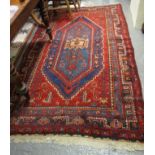 Middle Eastern design carpet on a red field with stylised flowers and geometric decoration. (B.P.