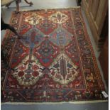 Middle Eastern red ground rug decorated with stylised panels of flower heads and animals.