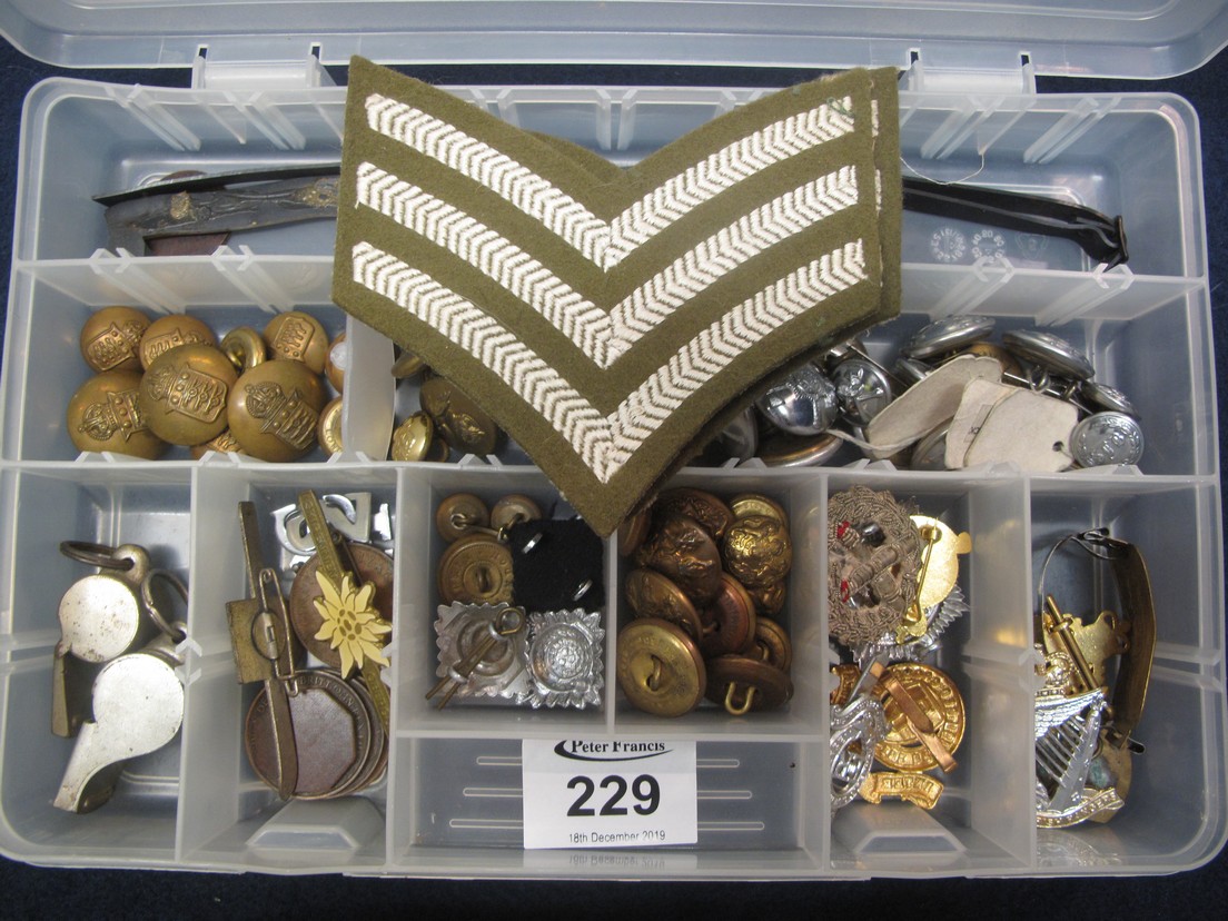 Plastic box containing assorted military cap badges, the Acme thunderer and another similar whistle,