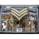 Plastic box containing assorted military cap badges, the Acme thunderer and another similar whistle,