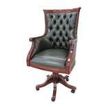 A reproduction Regency style carved mahogany revolving desk armchair, upholstered in green leather