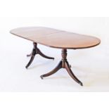 A Regency style mahogany oval dining table on two tripod supports on castors. L225cm, W98cm, H75cm