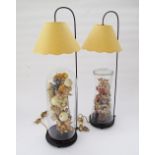 A pair of table lamps with hanging shades over glass domes covering flower arrangements - H80cm. (