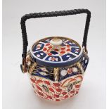 An English imari porcelain jar with cover and bamboo handle. The lid damaged and repaired. W18cm.
