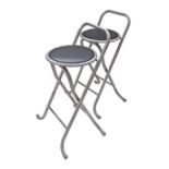 A pair of folding grey painted tubular steel high stools in black leatherette seat. The seat