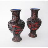 A pair of Chinese black on red carved lacquer cinnabar vases on brass base, the interior and base