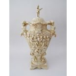 An Italian porcelain urn with cover, decorated with cherubs and figures in relief. C1950s (damages