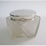 A modern etched frosted glass jar lidded with a silver cup.