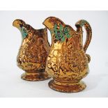 Two Victorian Staffordshire copper lustre pitcher jugs decorated with figures in relief and green