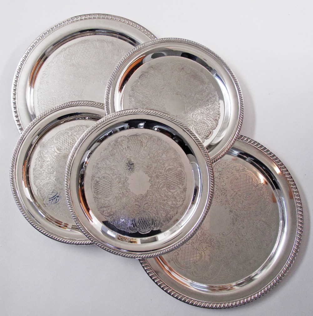 A collection of silver plated round serving dishes with engraved decoration and gadrooned rims.