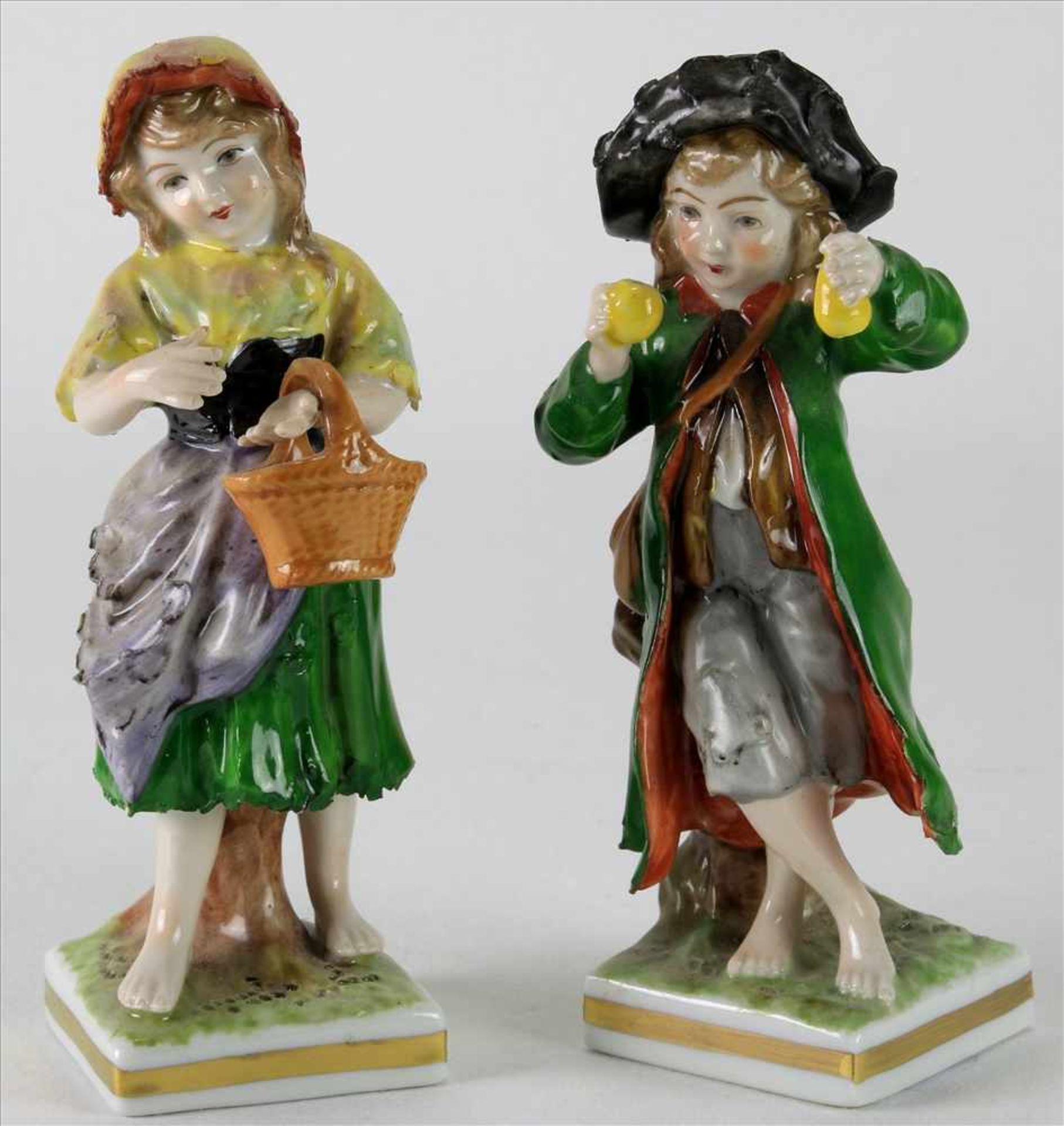 Paar PorzellanfigurenRudolstadt um 1900. Junge mit Äpfeln und Mädchen mit Korb. Polychrome Staffage.