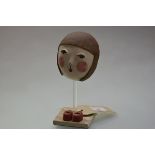 Midori Takaki (Contemporary), Ceramic Mask with Red Shoes, on a travertine stand. Height overall