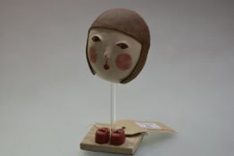 Midori Takaki (Contemporary), Ceramic Mask with Red Shoes, on a travertine stand. Height overall