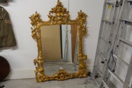 A giltwood mirror in the Rococo taste, the bevelled shaped plate within a conforming frame