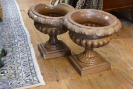 A pair of glazed stoneware campana form garden urns, each with lappet rim and part reeded bowl, on a